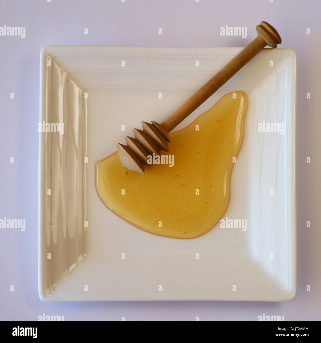 Australian honey on a white plate with a honey dipper. Stock Photo