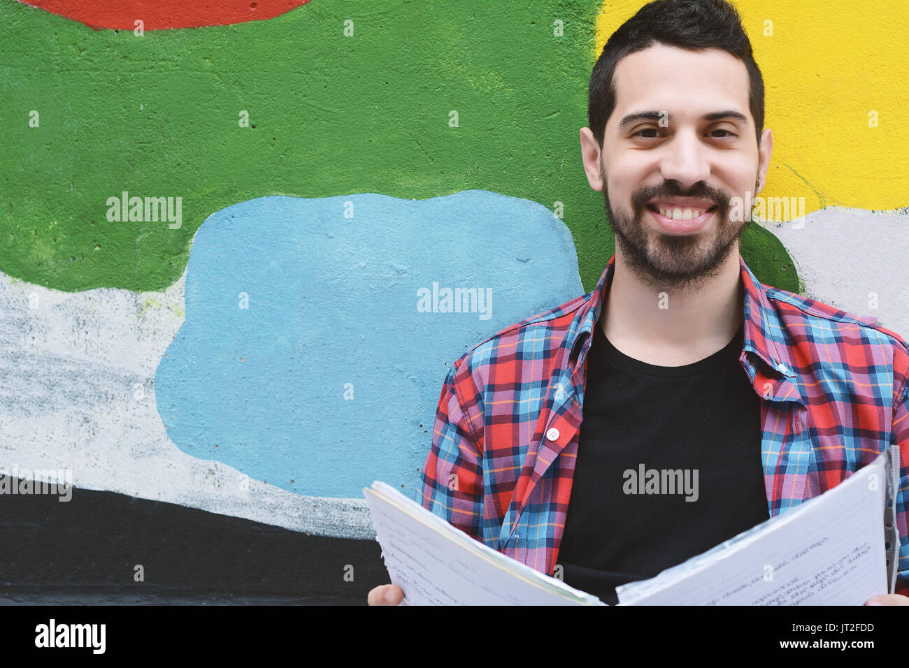 Portrait of young latin man against a graffiti wall. Urban scene Stock
