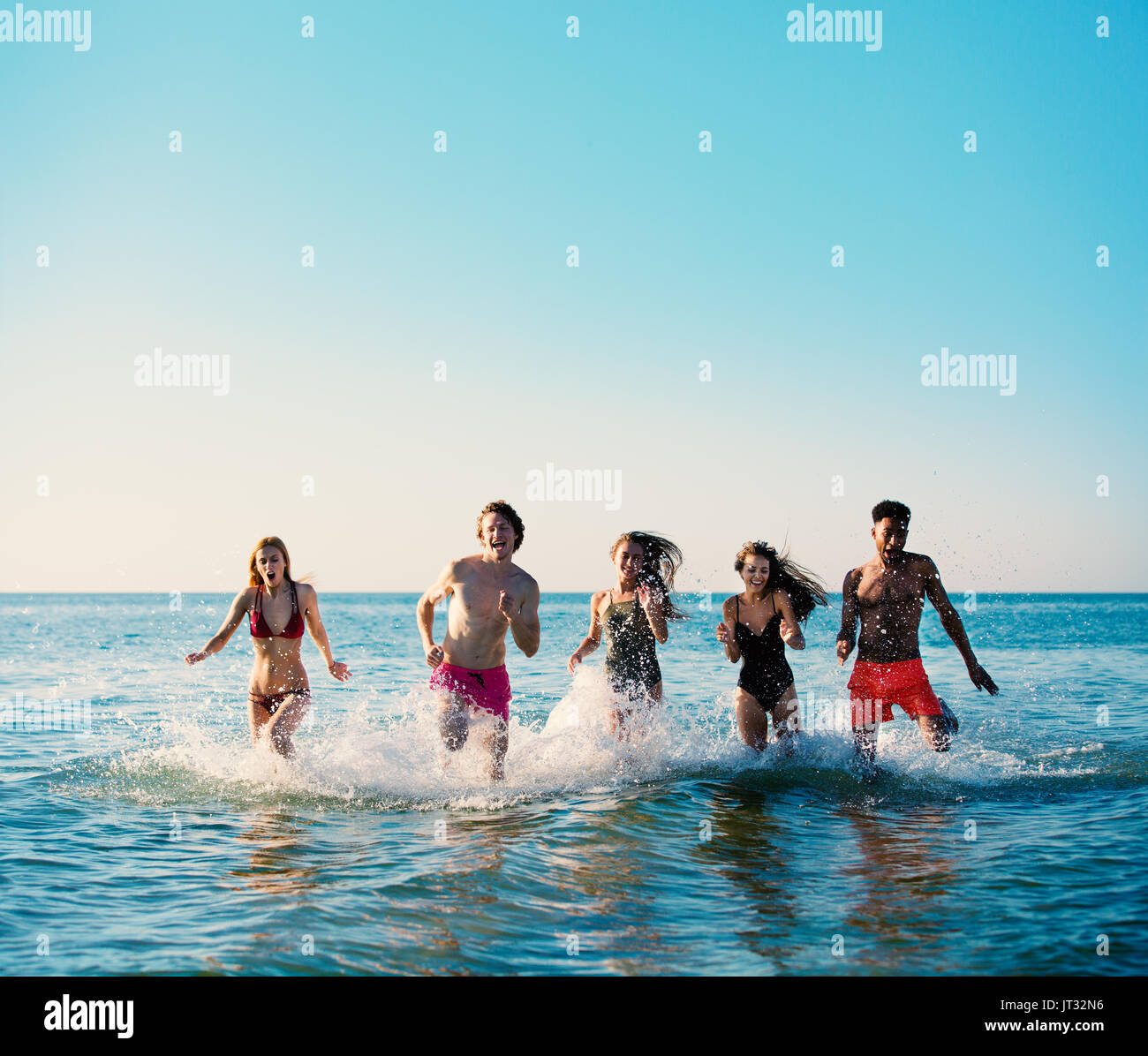 Group of friends run in the sea. Concept of summertime Stock Photo