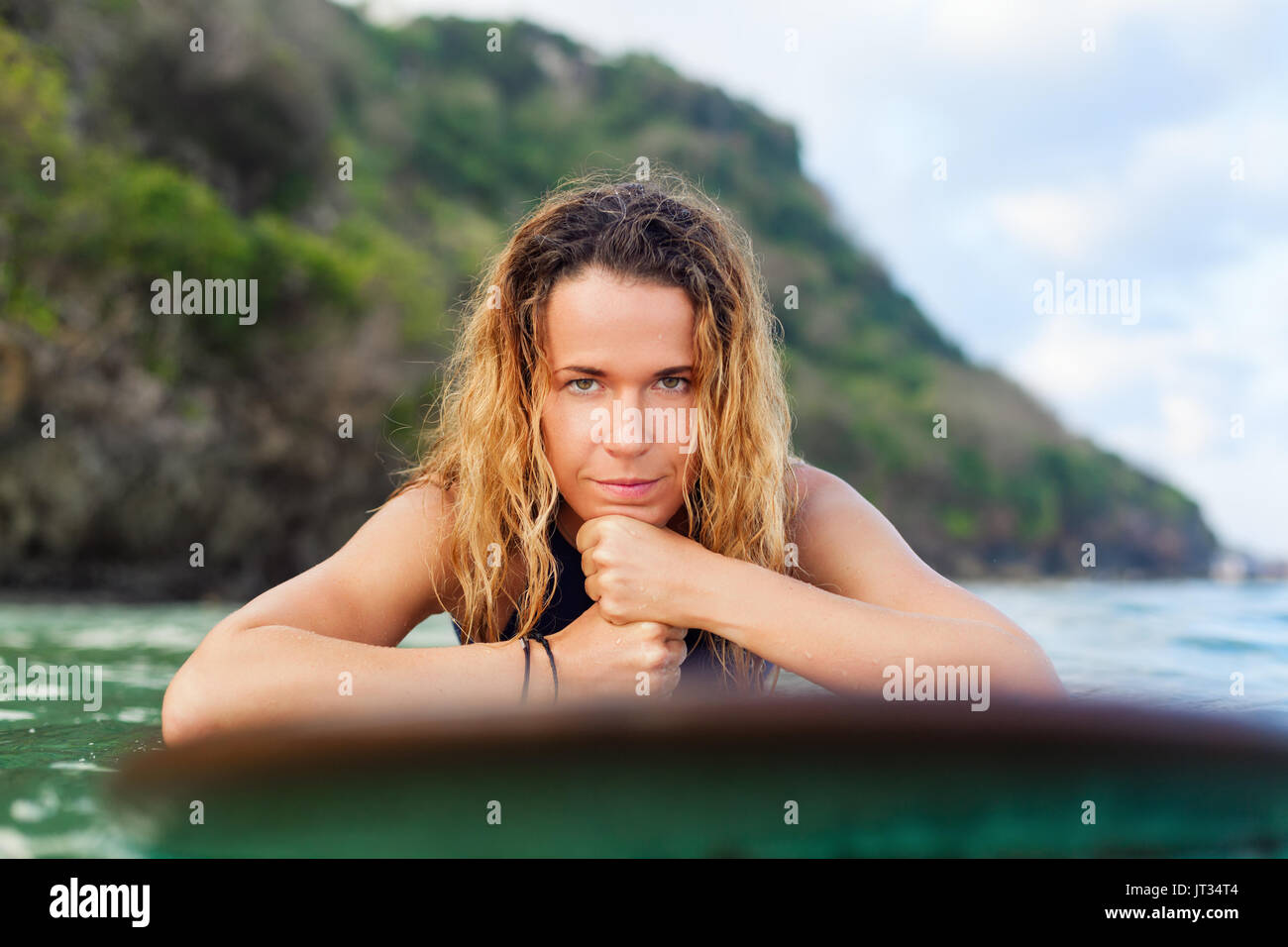 Happy girl in bikini have fun before surfing Surfer lie on surf board, look at sunset sky. People in water sport adventure camp, extreme activity on f Stock Photo