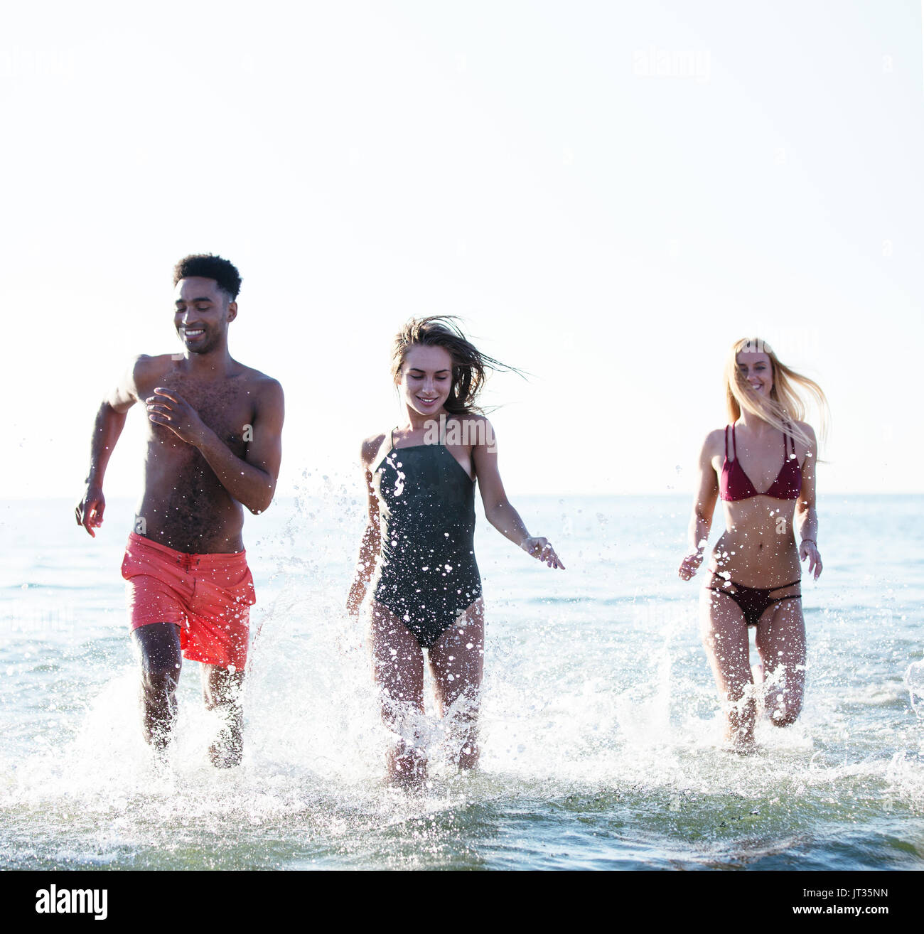 Group of friends run in the sea. Concept of summertime Stock Photo
