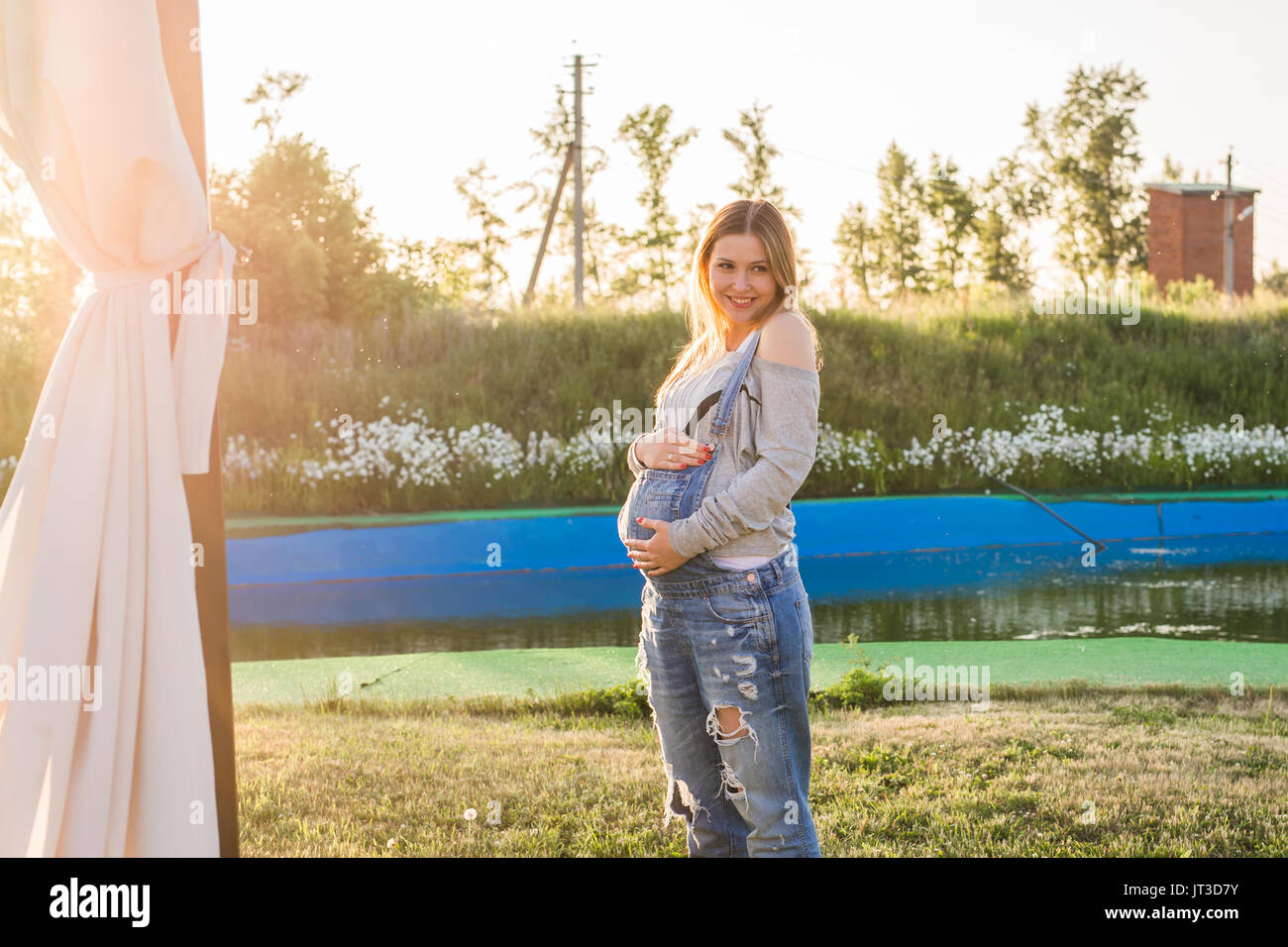 Pregnant woman hugging her stomach outdoors Stock Photo - Alamy