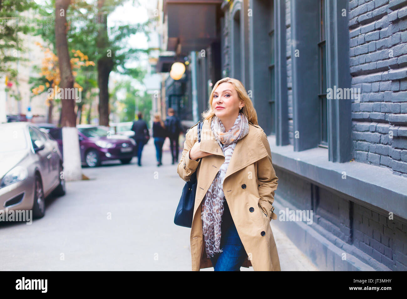 Middle age women goes through the city and smiles. Happiness concept. Stock Photo