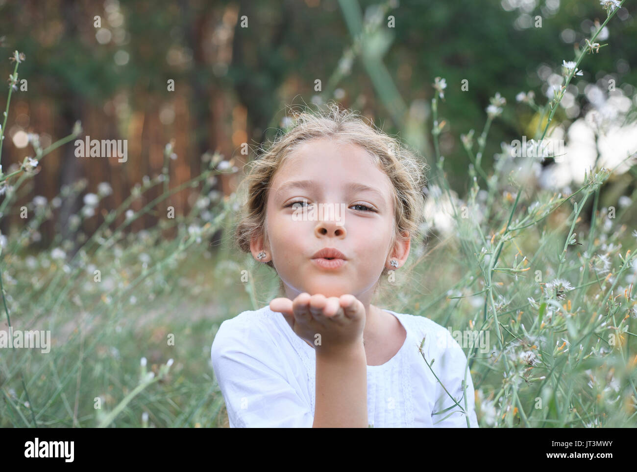 Portrait of a cute little girl sends an air kiss on the nature in