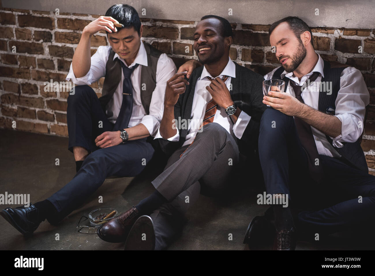 group of tired stylish businessmen resting together after work Stock Photo