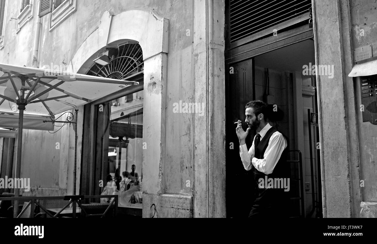 Rome Italy July 2017 - Restaurant worker takes a cigarette break on the street Stock Photo