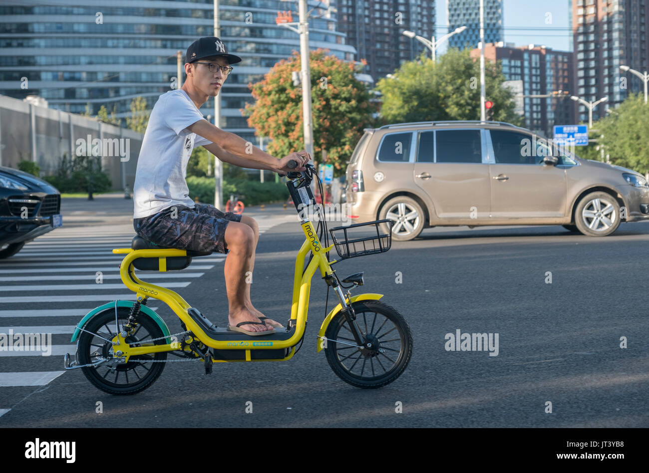 A man rides shared motorbike on a street in Beijing, China. 06-Aug-2017 Stock Photo