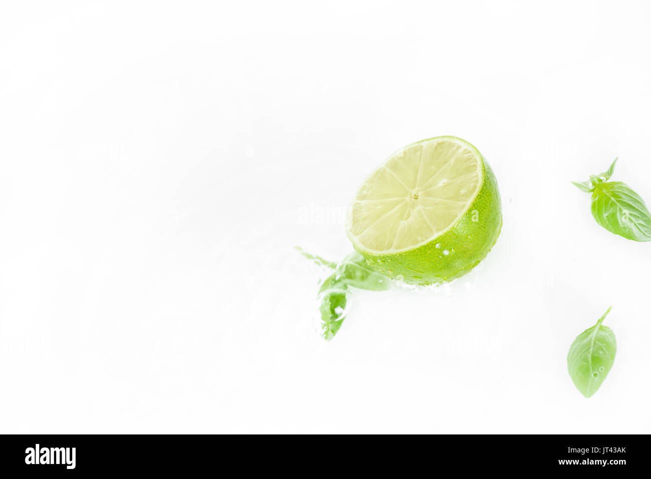 half of lime with green leaves and water drops isolated on white, fresh fruits background Stock Photo
