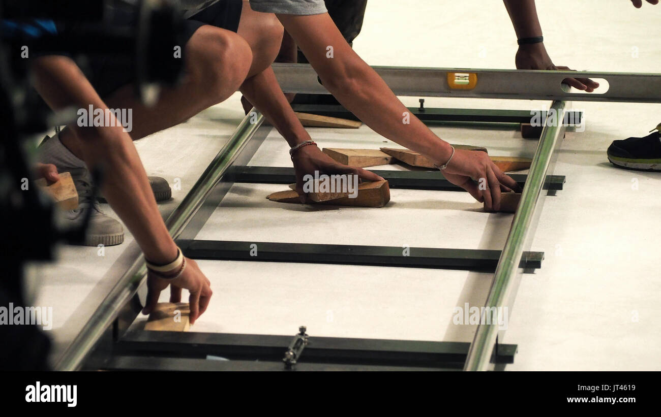 Behind the scenes of production team setting dolly track for camera equipment and video shooting in a big studio. Stock Photo