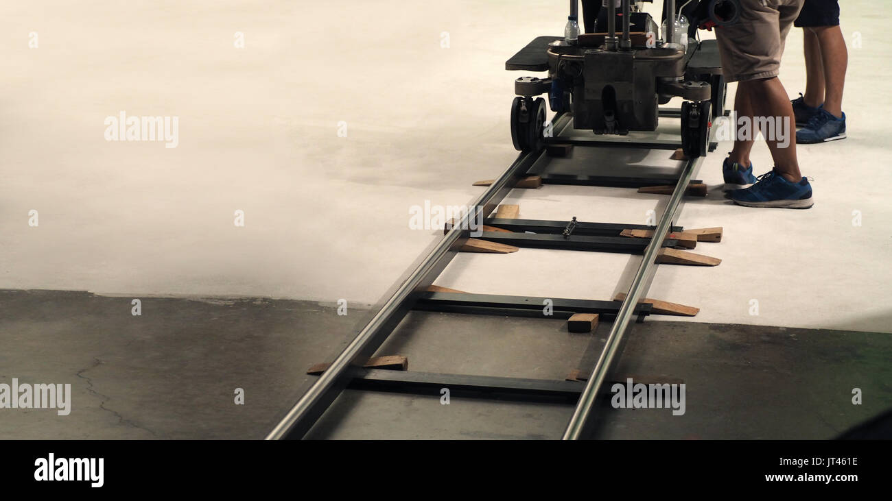 Behind the scenes of production team setting dolly track for camera equipment and video shooting in a big studio. Stock Photo