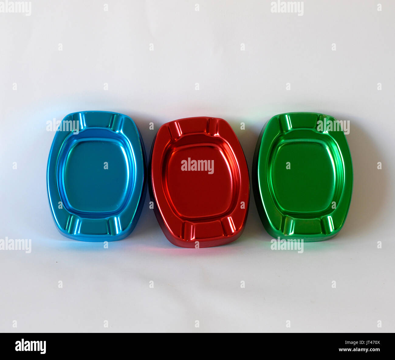 Three colorful ashtrays made by anodized aluminum, colors blue, red and green. For cigarettes smokers. Smoke Cigarette Stock Photo