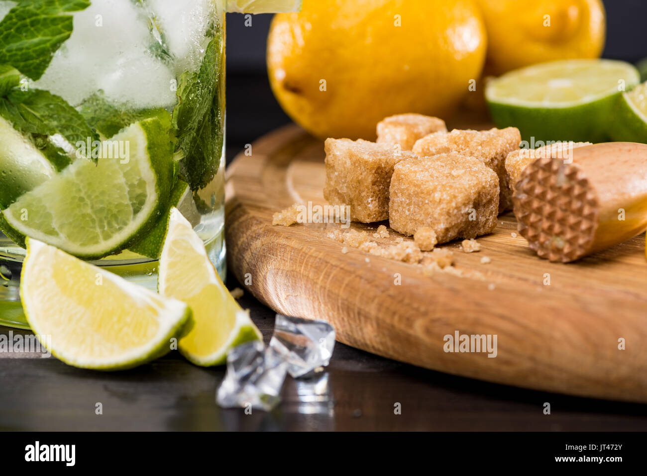 Close-up view of mojito cocktail in glass, crushed sugar, limes and ice cubes on table, cocktail drinks concept Stock Photo