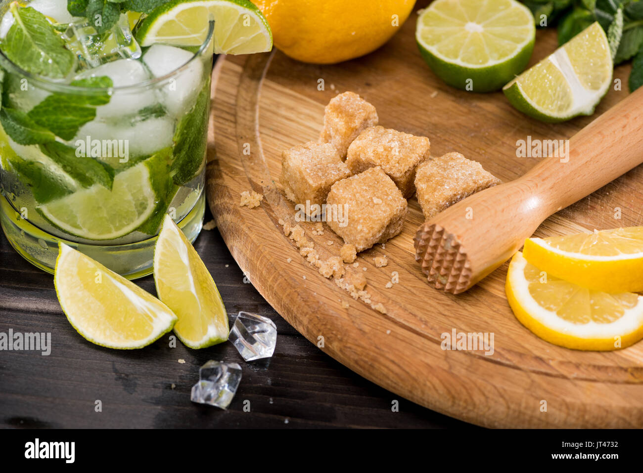 Close-up view of mojito cocktail in glass, crushed sugar, limes and ice cubes on table, cocktail drinks concept Stock Photo