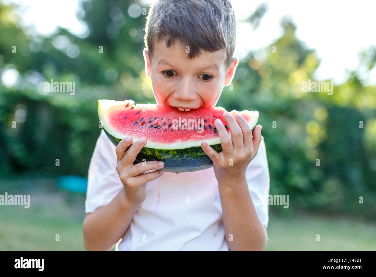 Happy little caucasian kid bite into watermelon outdoor Stock Photo