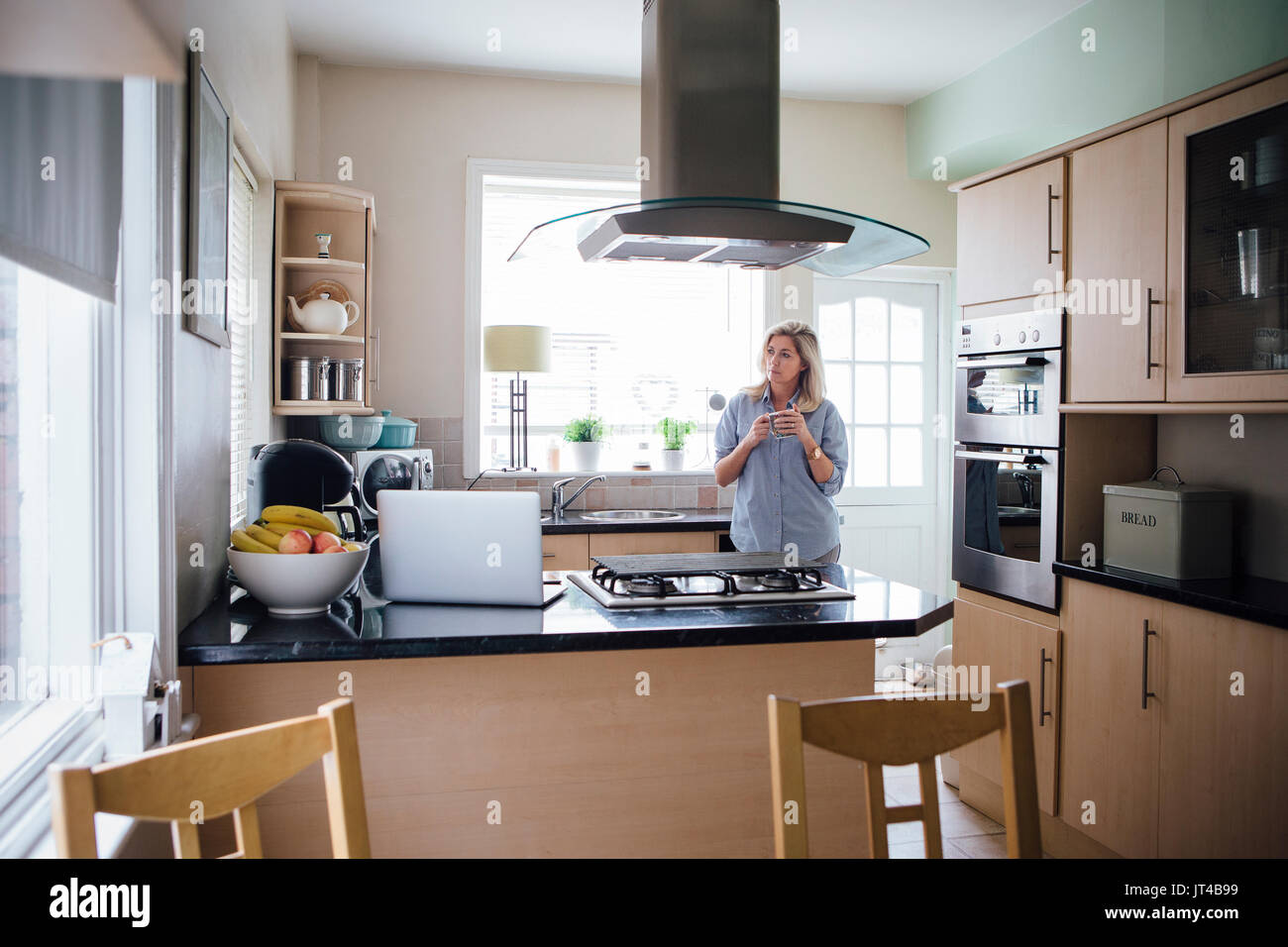 Woman in her kitchen with a cup of tea. She is having some time to herself. Stock Photo