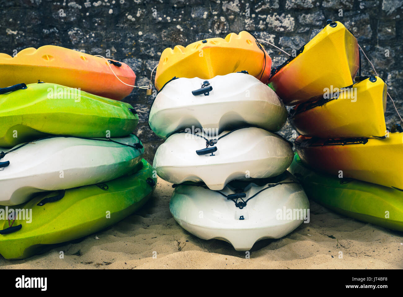 Stacked white, green and orange kayaks on a beach Stock Photo - Alamy