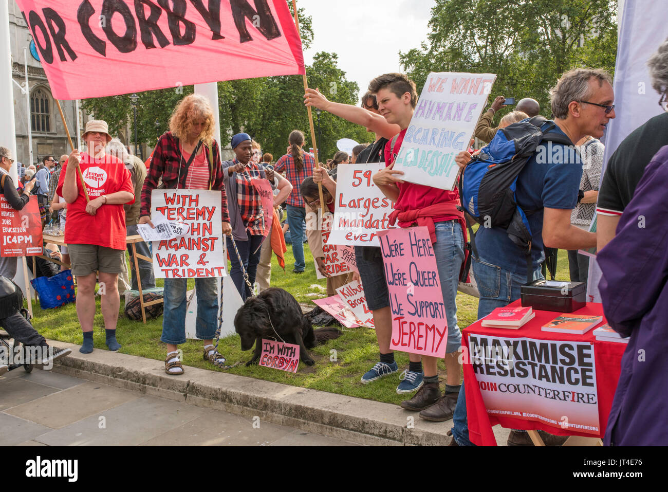 Women supporters of Jeremy Corbyn with different banners pledging allegiance to the Labour leader . A black Labrador has its own sign around its neck. Stock Photo
