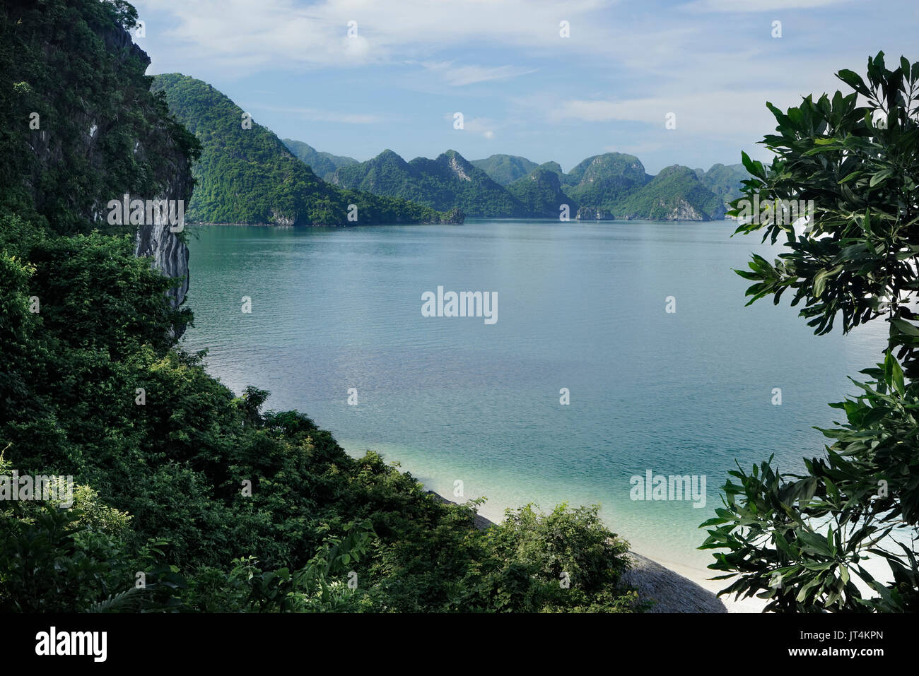 View of green islands in Halong Bay at day from a distance with empty white sand beach and turquoise water, UNESCO World Heritage Site, Vietnam, South Stock Photo
