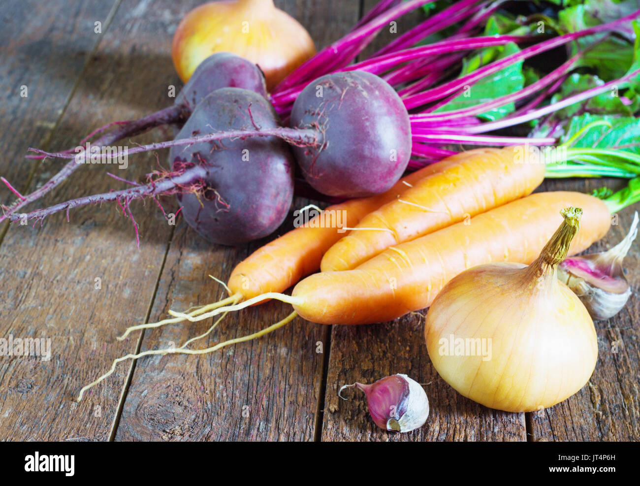 Different fresh young vegetables beets carrots, tomato, garlic, onions lie on a wooden table. rustic style Stock Photo
