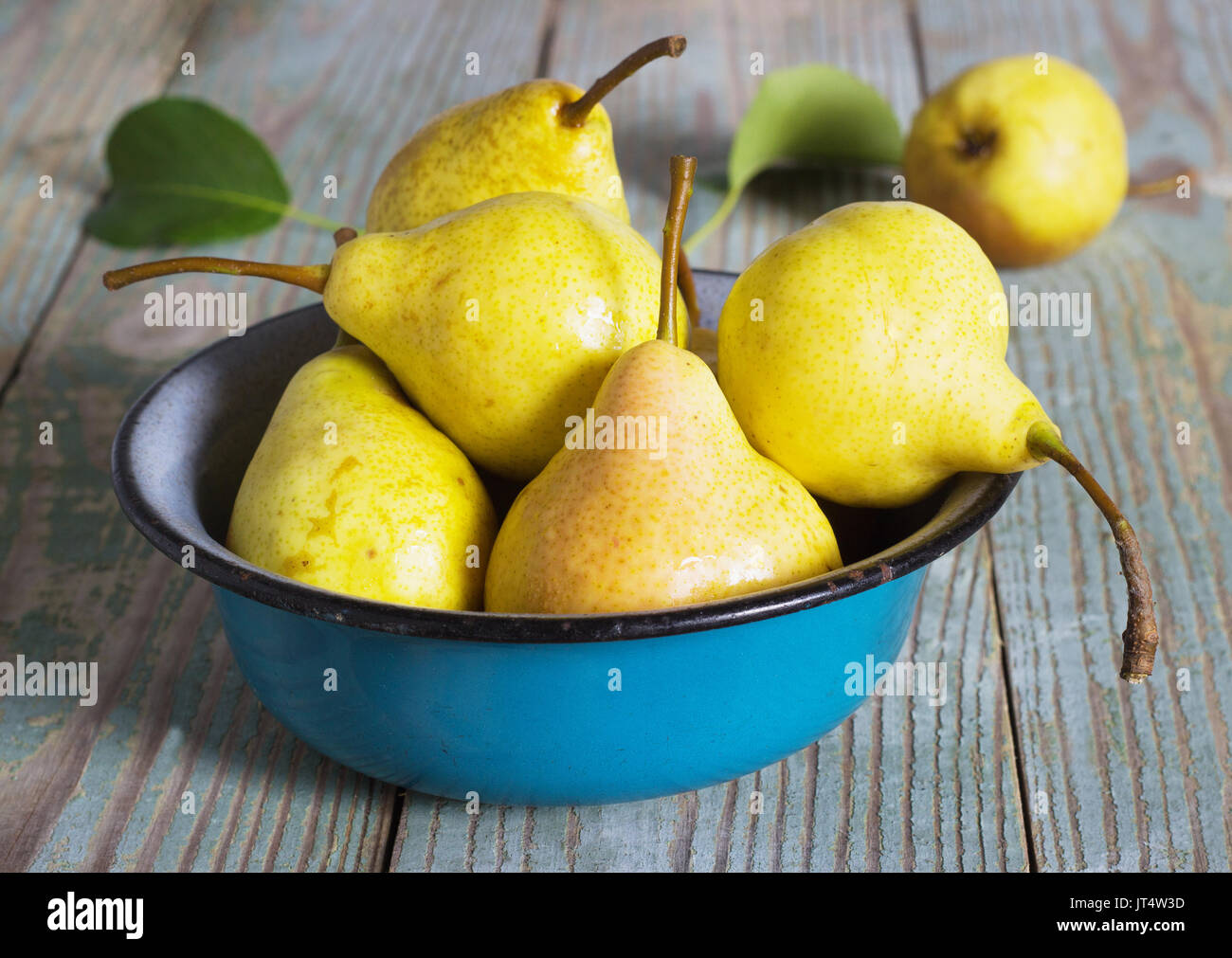 yellow pear in a metal bowl on a wooden table Stock Photo