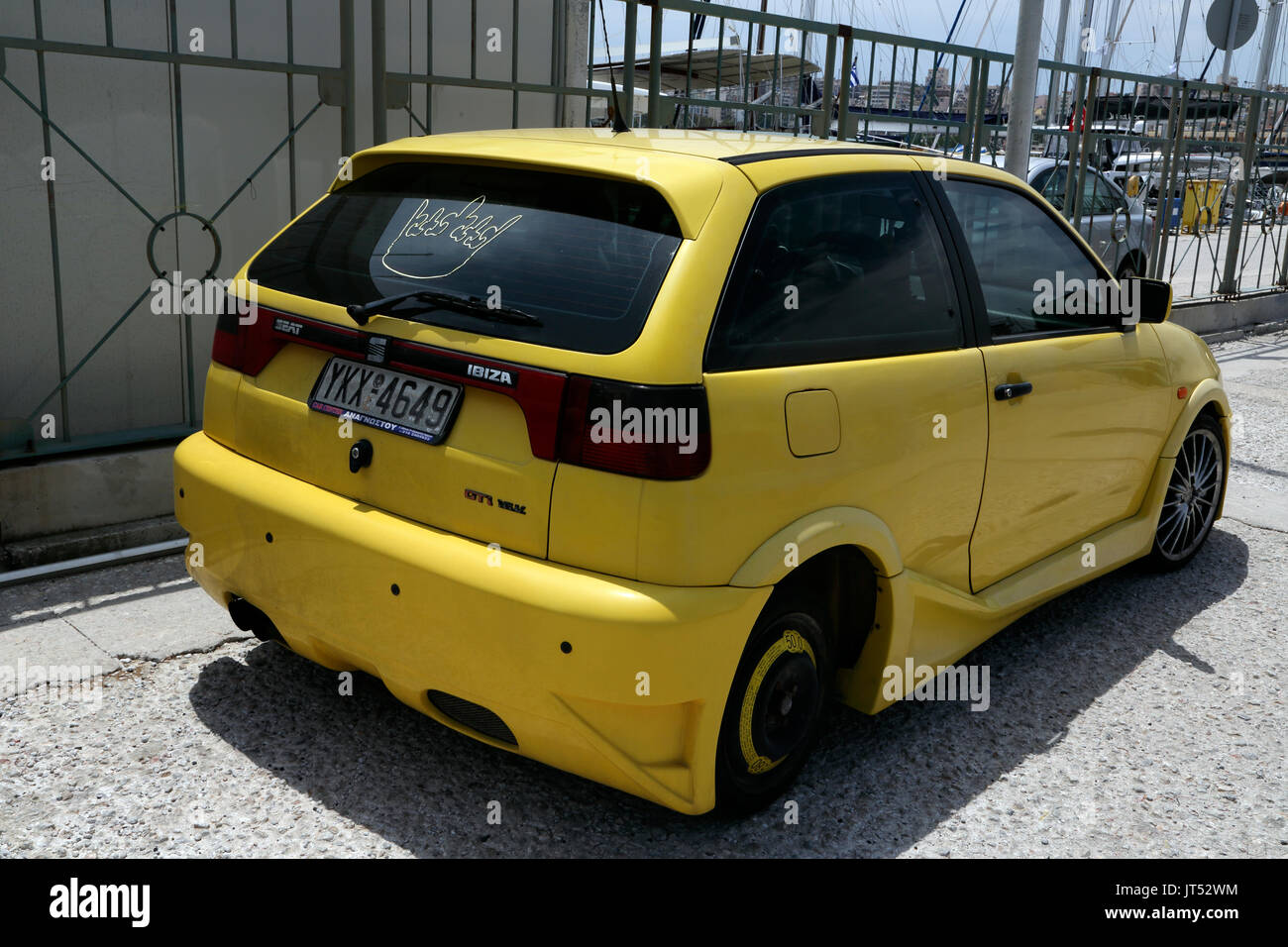 Lavrio Port Attica Greece bright yellow Seat Ibiza car parked by Port crown sticker on rear window Stock Photo