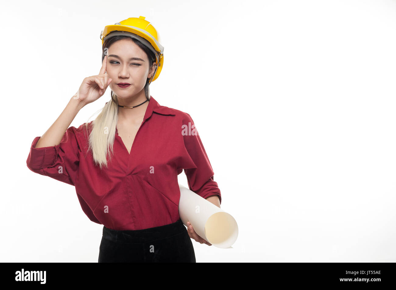 Young Asian woman architect with red shirt and yellow safety helmet thinking while carrying blueprints. Industrial occupation people concept Stock Photo