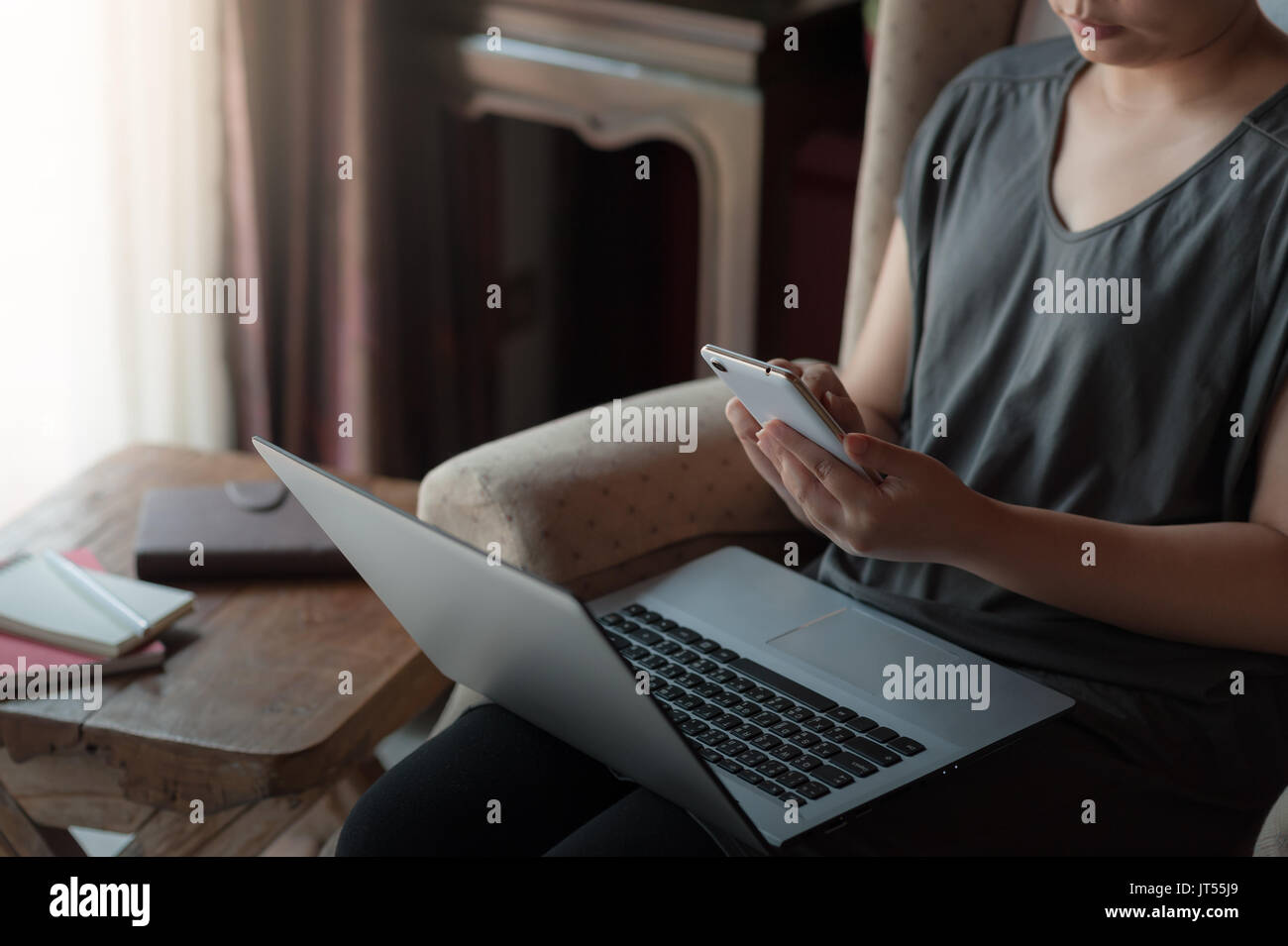 Woman freelancer using smartphone for social network while working with laptop computer. Online business and self-employed concept Stock Photo