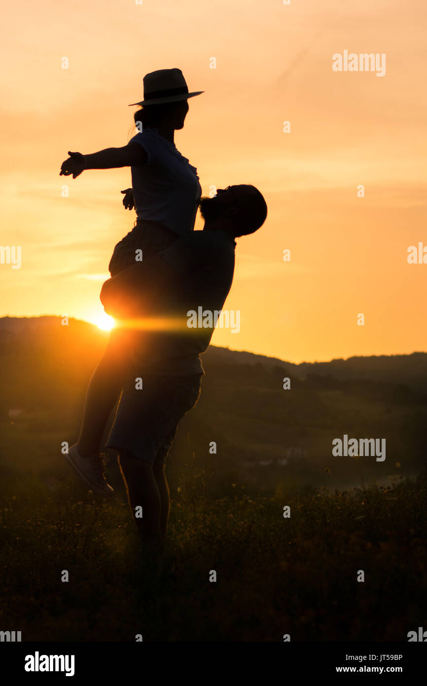 Happy couple silhouette with romantic sunset with golden sky Stock Photo