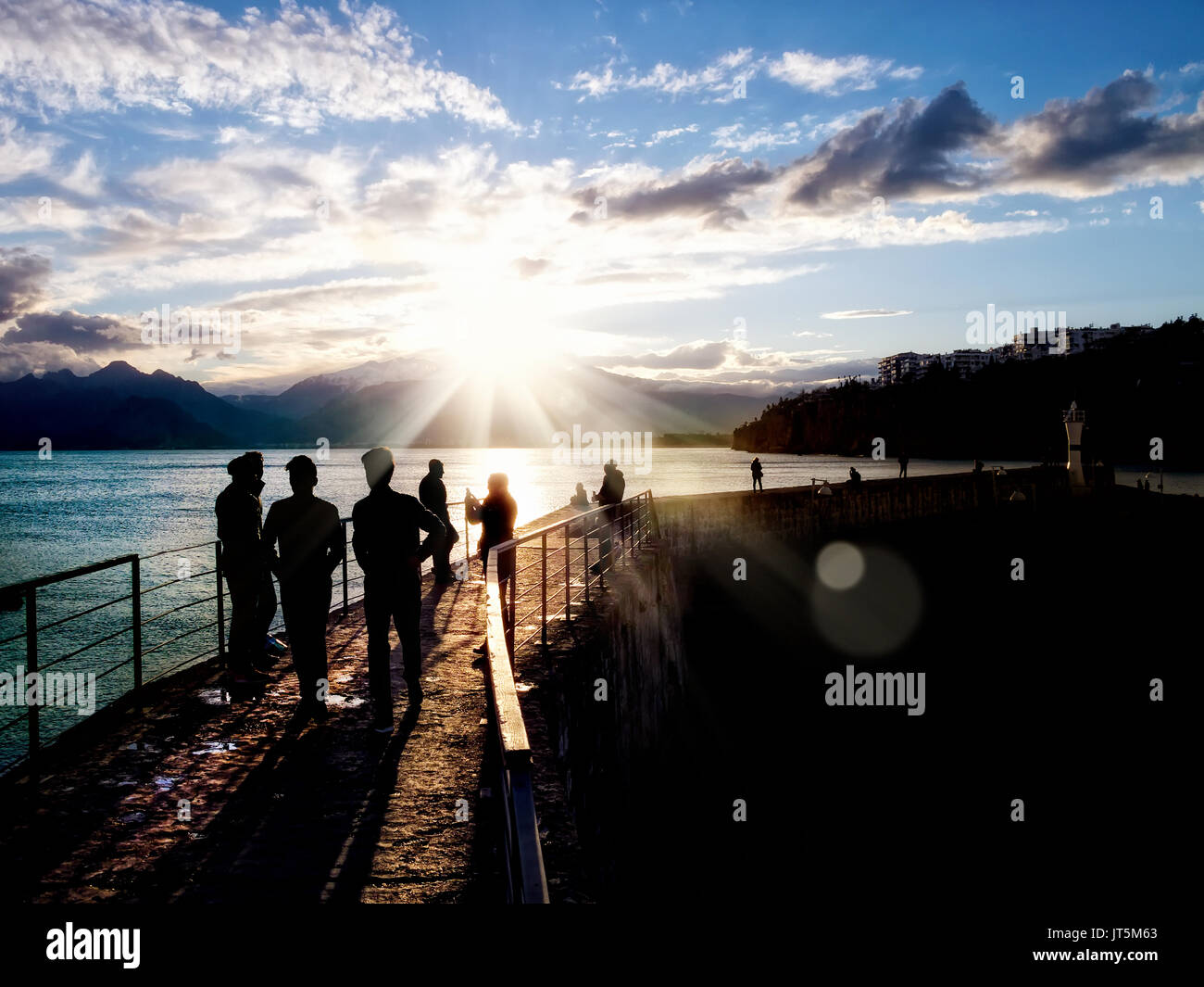 silhouetted people walking on street over sunset sky with sunbeam Stock ...