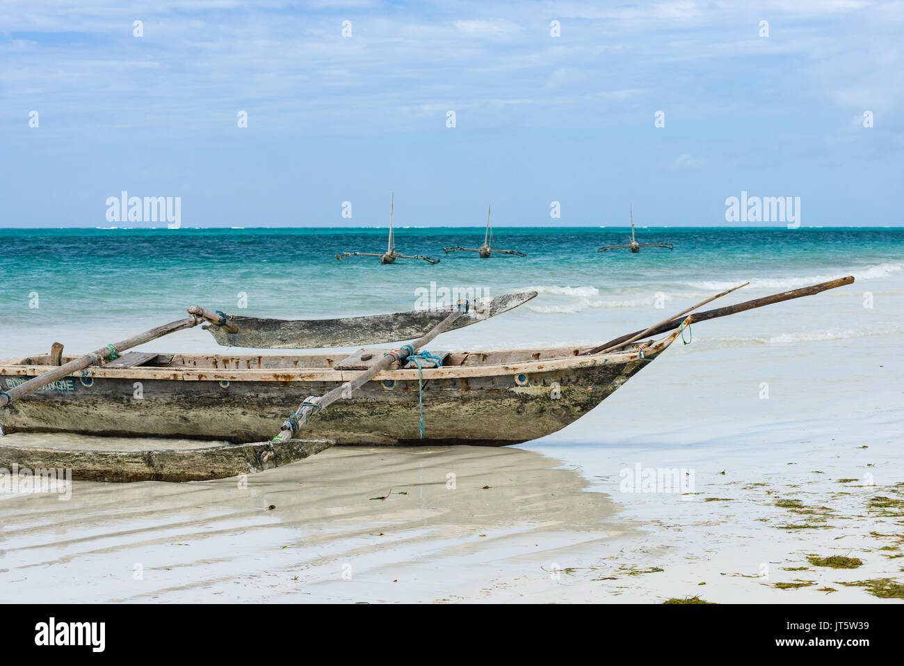 Traditional dhow fishing boats by shoreline and in ocean, Diani beach, Kenya Stock Photo