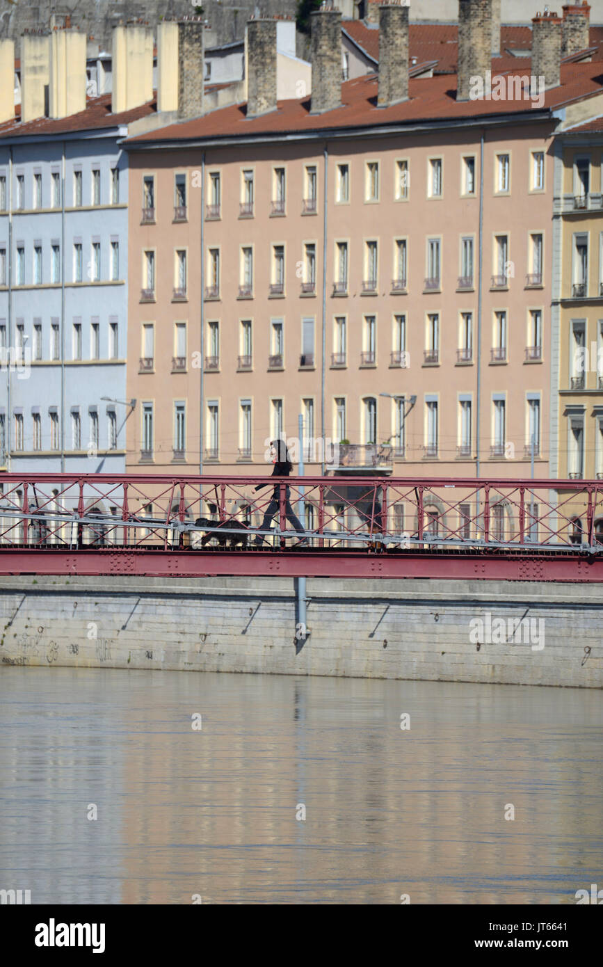 Lyon (south-eastern France): real estate, buildings along the Quais de Saone walkway, with a woman having a walk with her dog on the footbridge of the Stock Photo