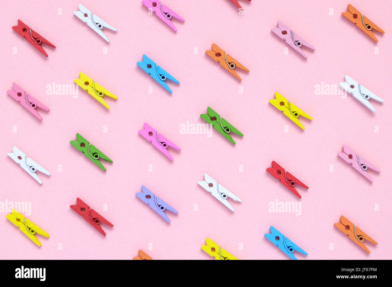 Colorful wooden clothespins on pink paper background Stock Photo