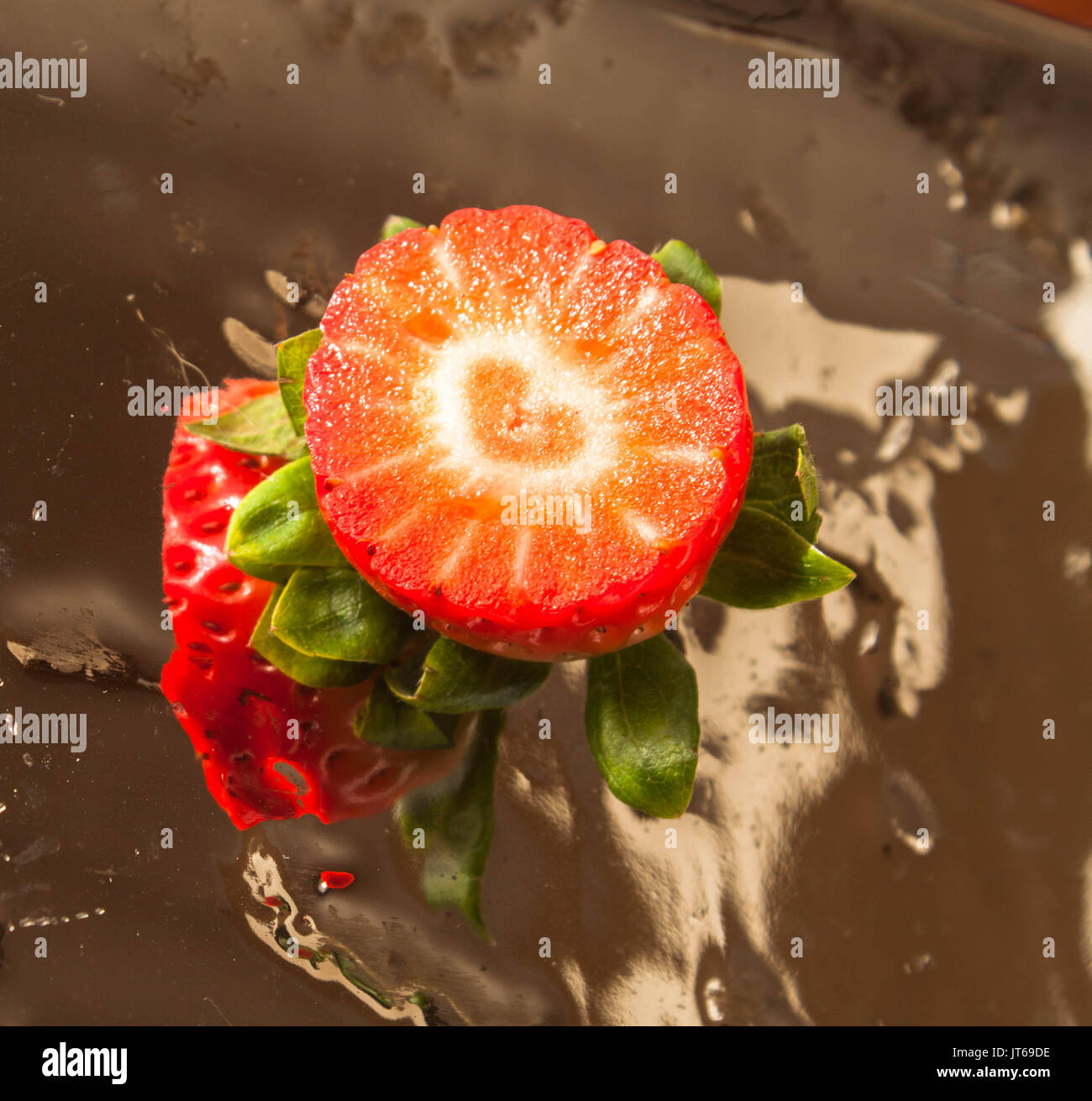 Strawberry slice with a heart shape inside in a bright mirror surface as healthy life and food concept Stock Photo