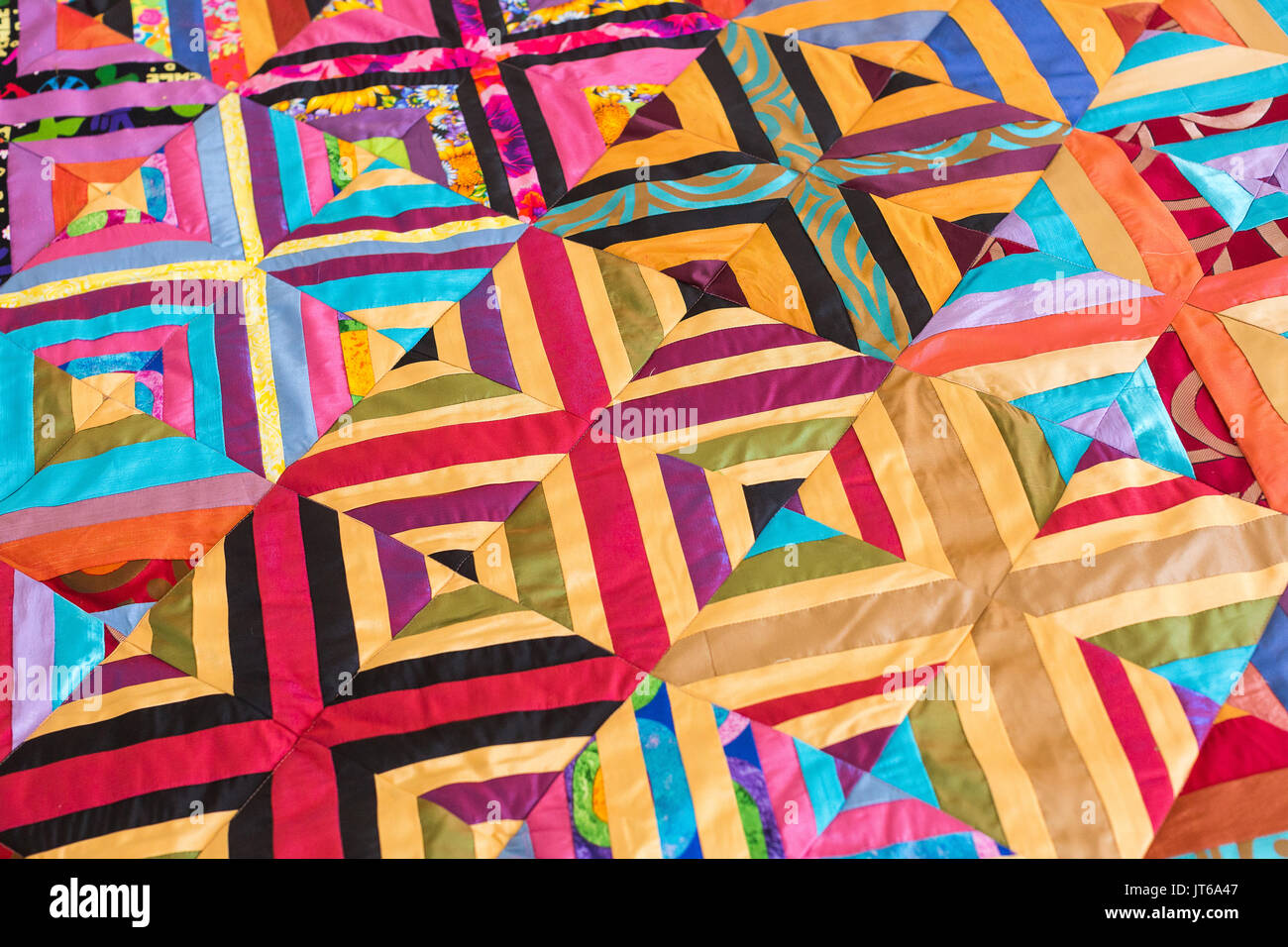 housekeeping, sewing, retro concept. a bright perfectly symmetrical and leveled pattern on the coverlet sewn at home from different fragments of fabrics captures the look Stock Photo