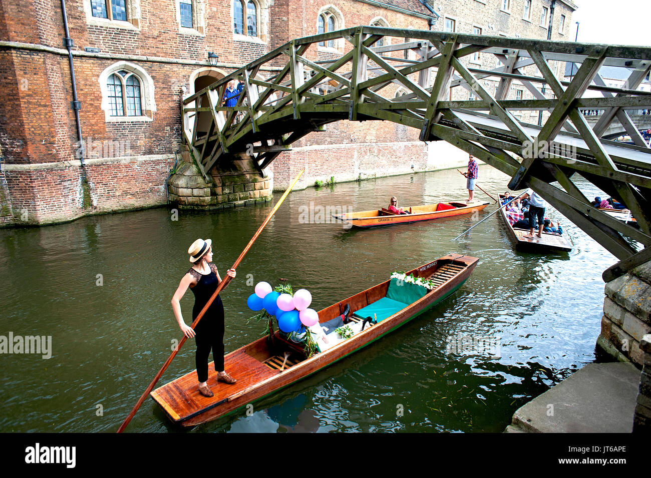A newly married couple take a river punt in Cambridge passing under the famous mathematical bridge at Queen's College, part of Cambridge University. Stock Photo