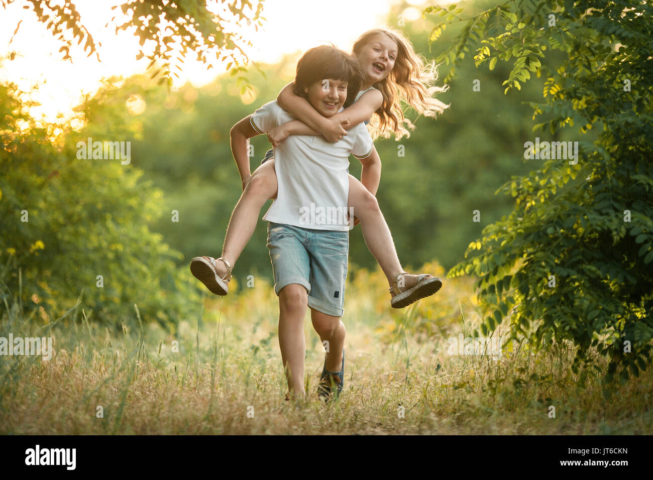 Little Boy Carries Girl On His Back In Forest They Laugh Fun First Love Stock Photo Alamy