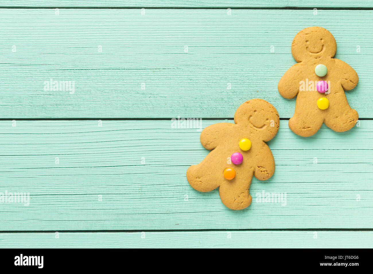 Two gingerbread men on colorful wooden table. Top view. Xmas gingerbread. Stock Photo