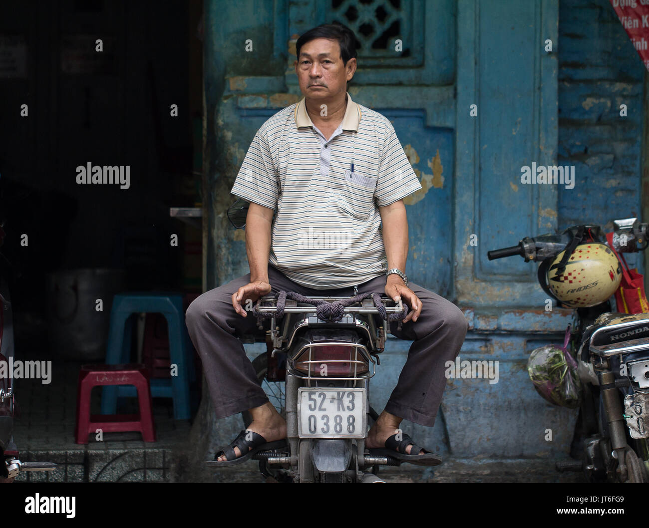 man vendor sitting on motorbike on street in Saigon Vietnam Stock Photo