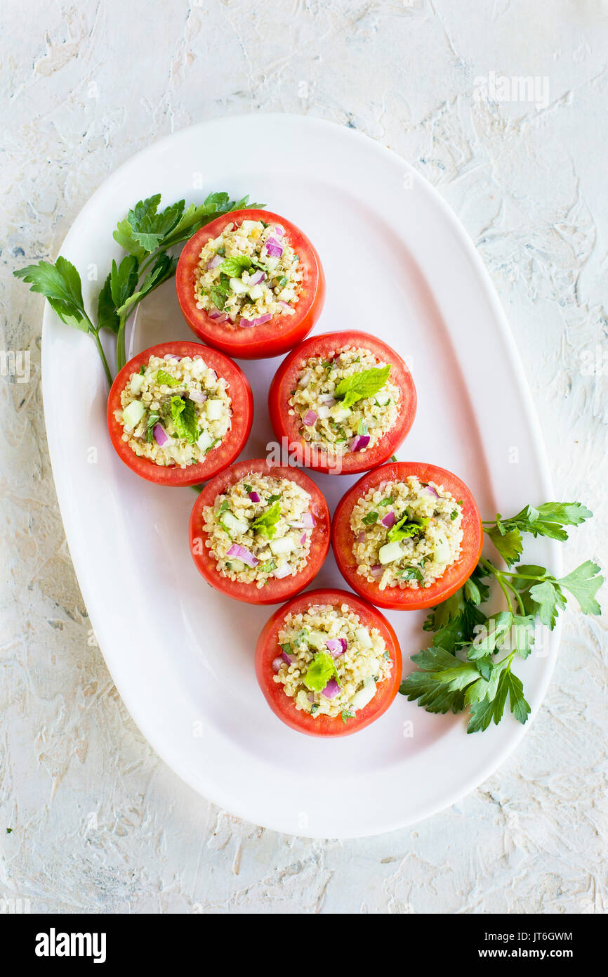 Quinoa Tabbouleh stuffed Tomatoes. Photographed on a white plaster background. Stock Photo