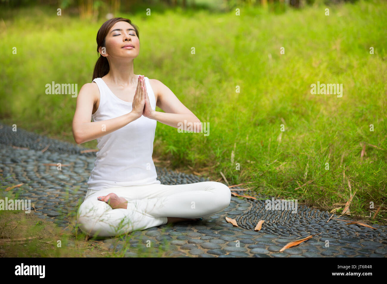 Young Asian woman practicing yoga in a garden. healthy lifestyle and relaxation Stock Photo