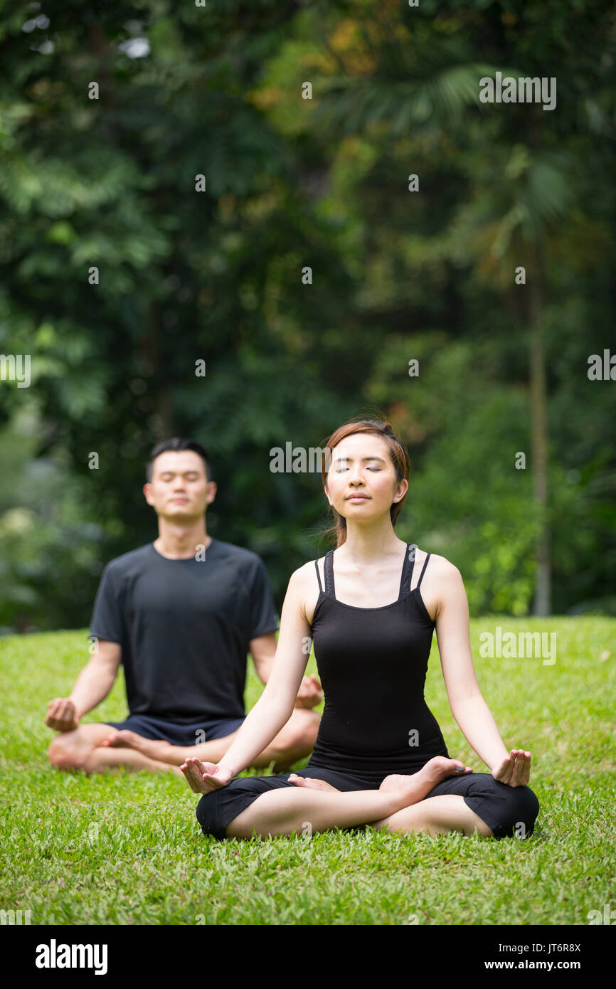 Asian Man and woman doing Tai Chi in a garden. Healthy lifestyle and relaxation concept. Stock Photo