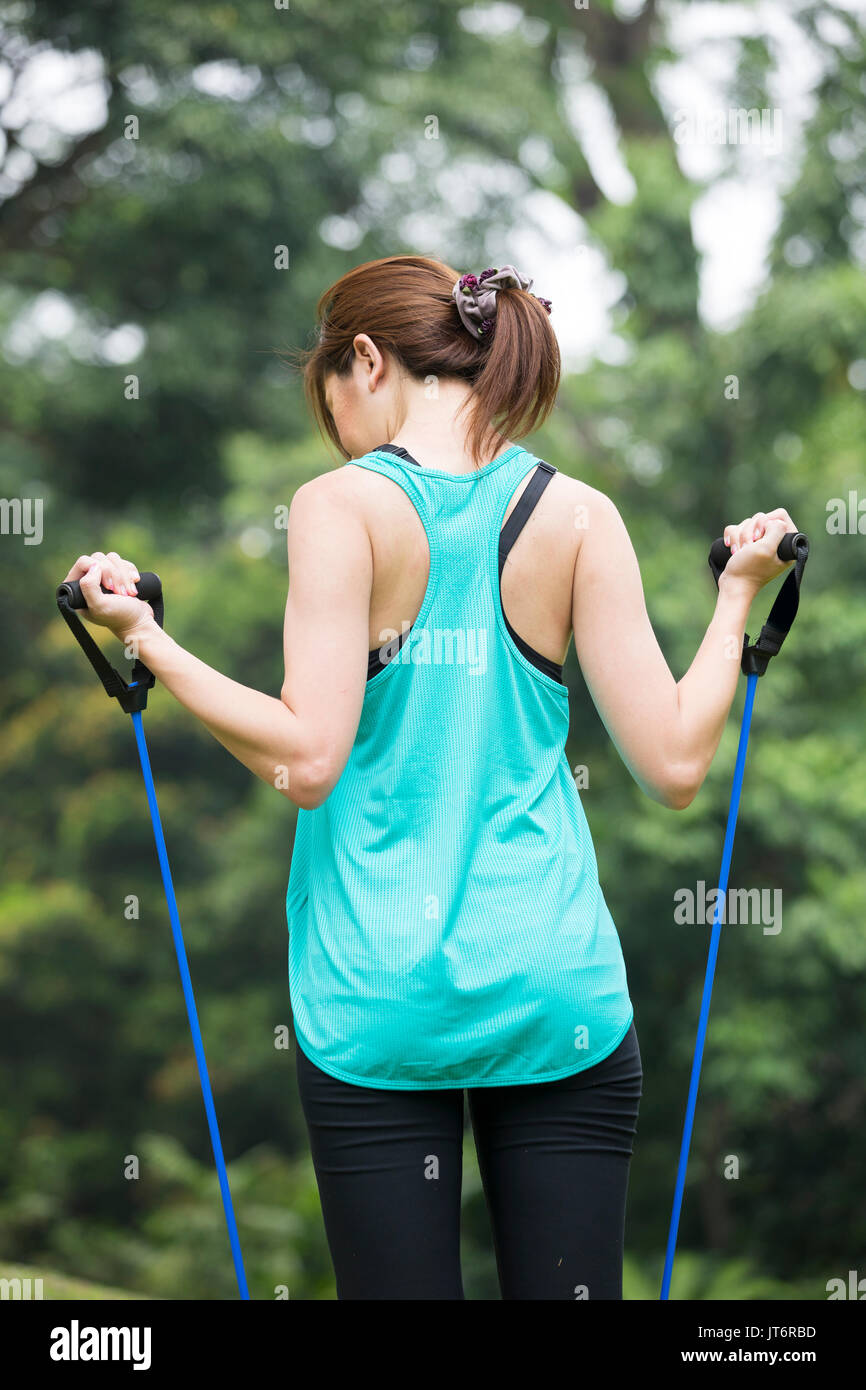 Athletic Asian woman exercising with a resistance band. Action and healthy lifestyle concept. Stock Photo