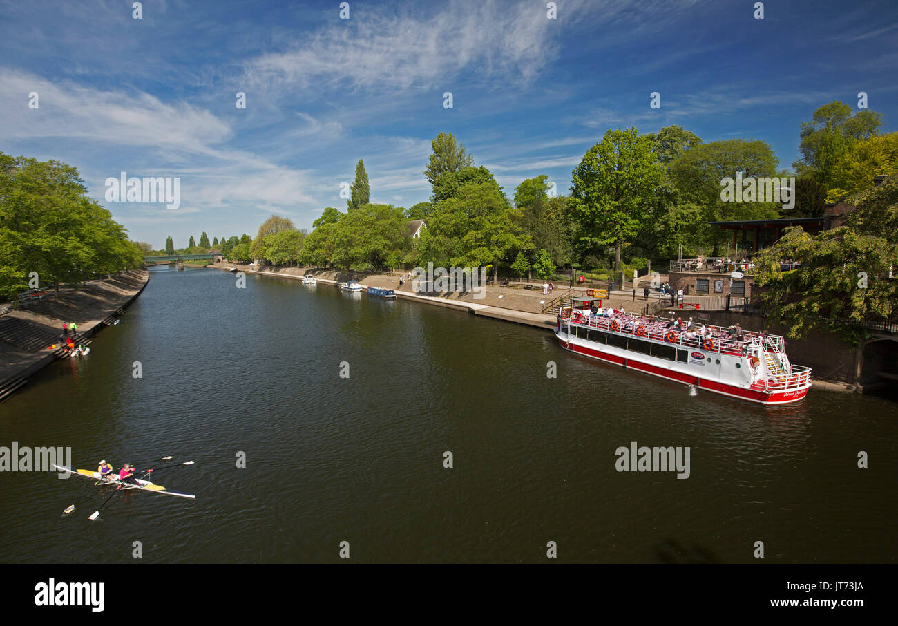 Tour boat with passengers on calm wide waters of tree-lined River Ouse under blue sky at York, England Stock Photo