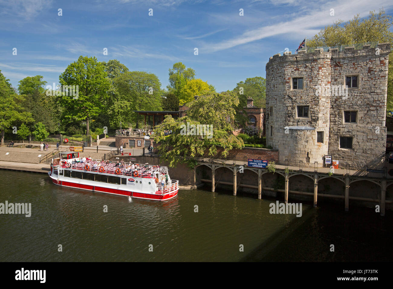 Tour boat with passengers on calm wide waters of tree-lined River Ouse under blue sky at York, England Stock Photo