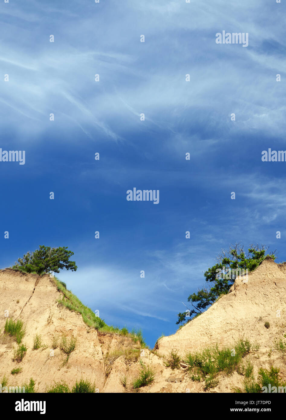 Clear blue sky over twin cliff peaks with trees Stock Photo