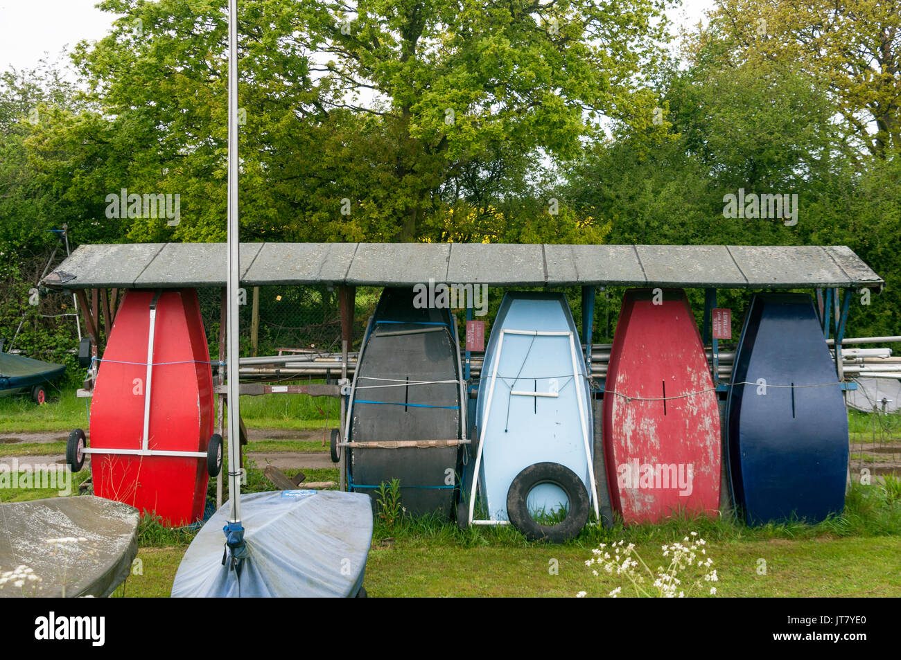 Water Sports, Small Boats, Sailing Boats, Sails Down, Boats Covered, Boats Stored on Land, Masts Down, Greenery Background, Boatyard, Docked Stock Photo