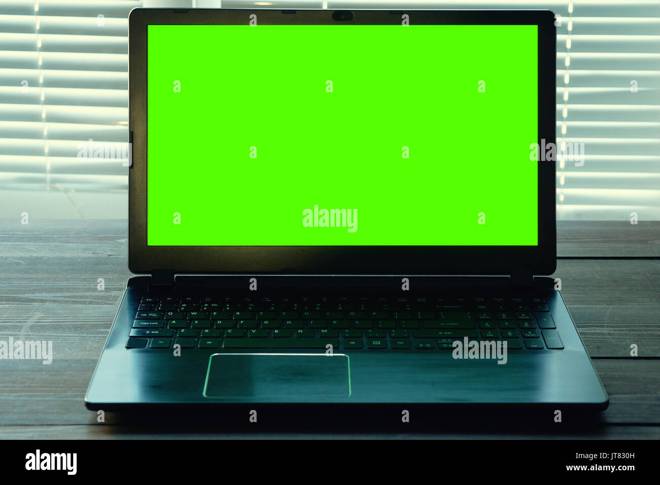 low key shot of opened black notebook on a dark desk with green screen for your data information. close view in office with closed blinds Stock Photo