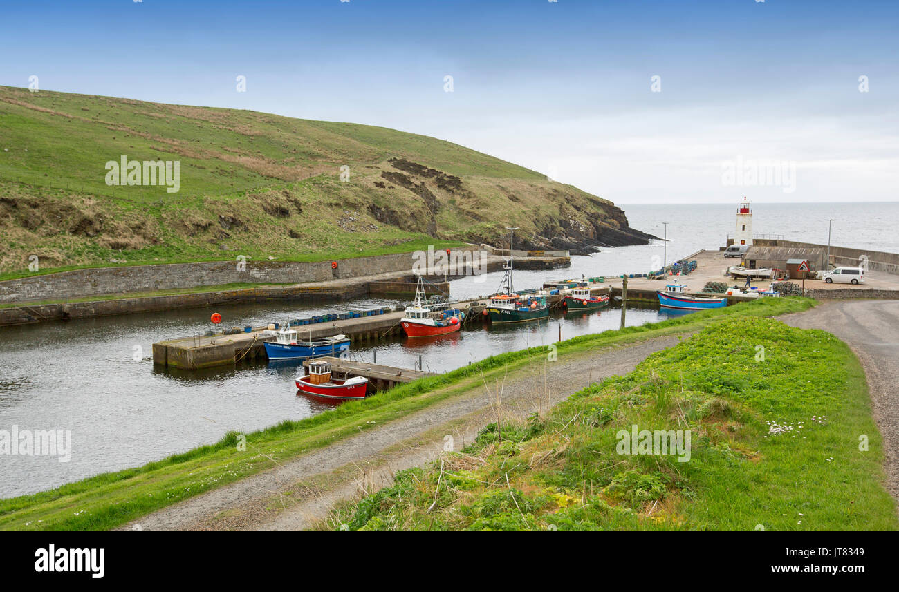 Panoramic view of colourful fishing boats on calm water of sheltered harbour under blue sky at village of Lybster, Caithness, northern Scotland Stock Photo