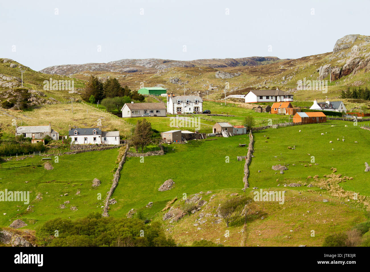 Crofters cottages and farmlands with green fields at base of rocky hills in Scottish highlands near Kinlochbervie, Scotland Stock Photo
