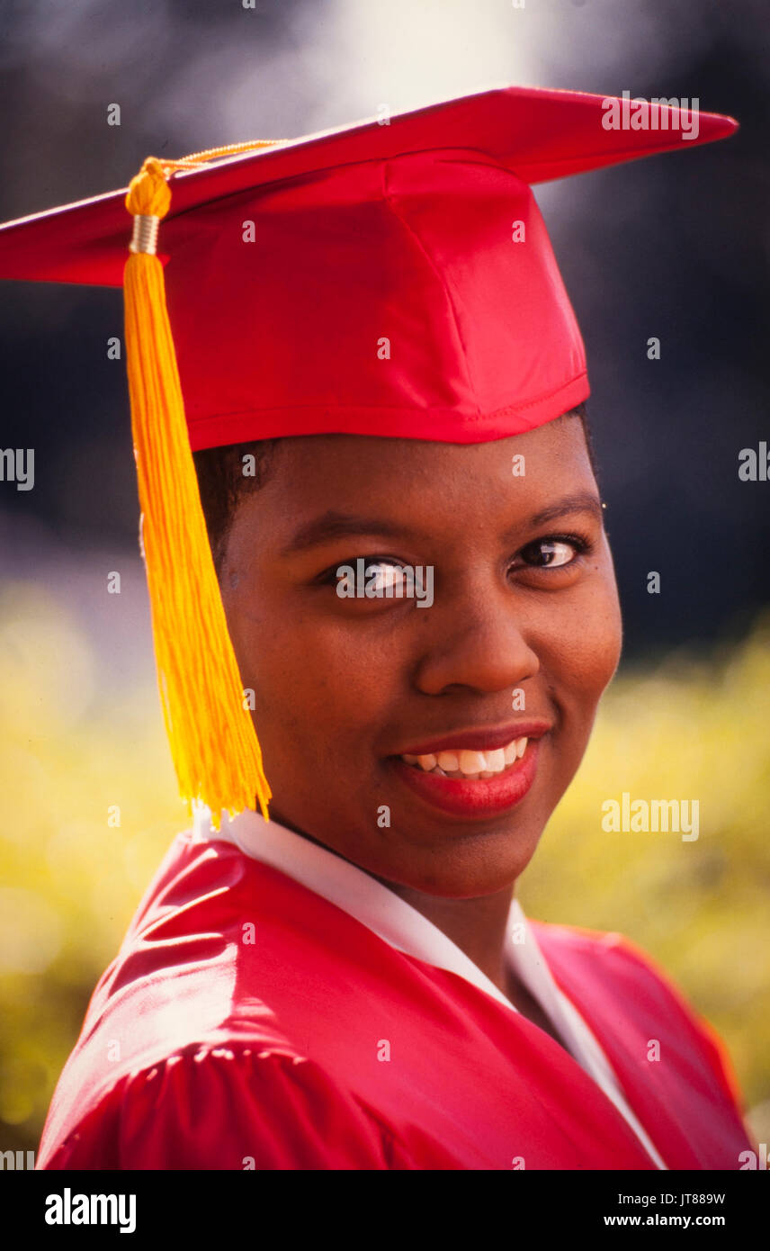 An African American graduate in her red cap and gown with a gold tassel. Stock Photo